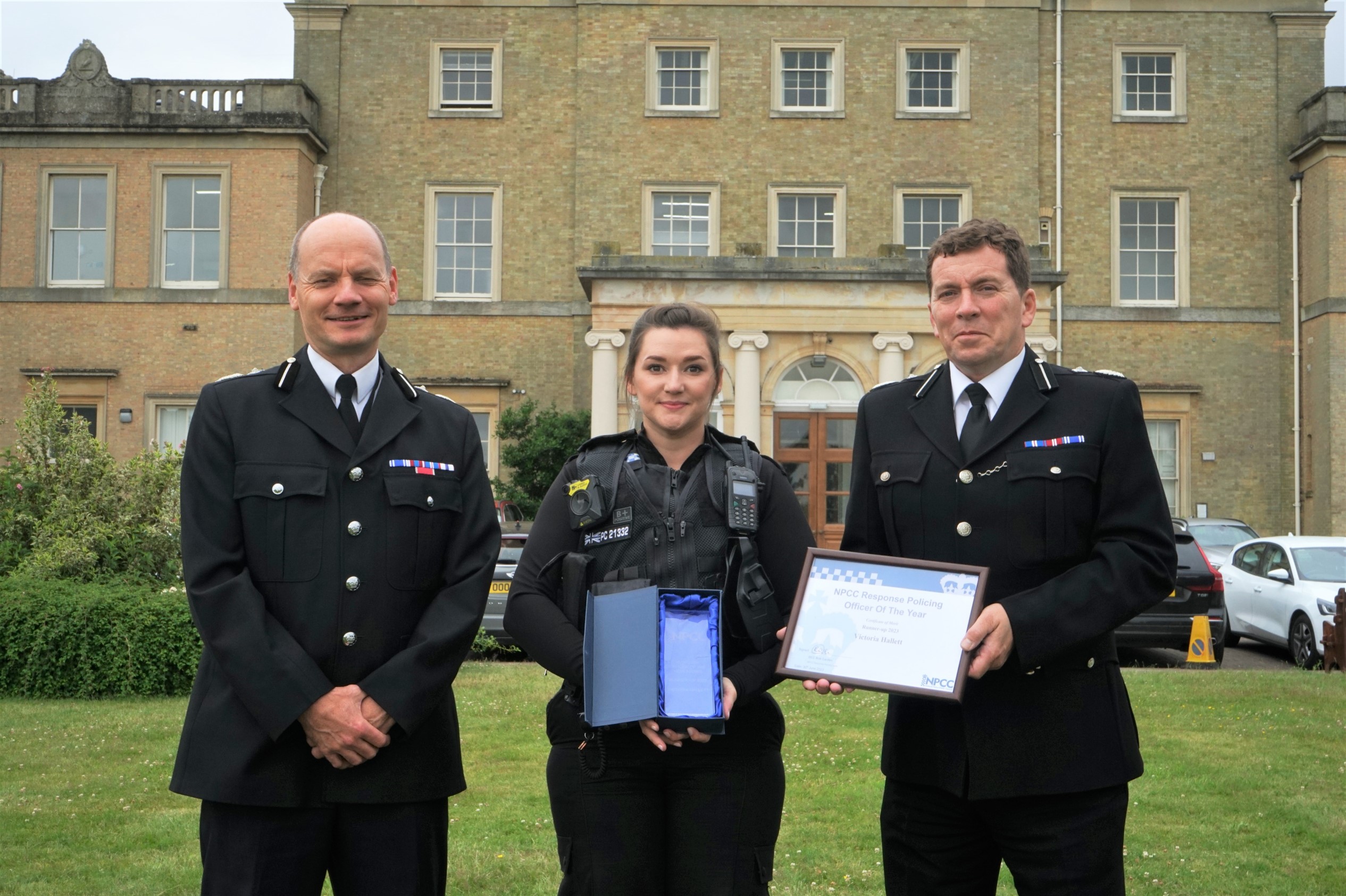 Sgt Vicky Hallett stands between two senior police officers (male) , holding her award