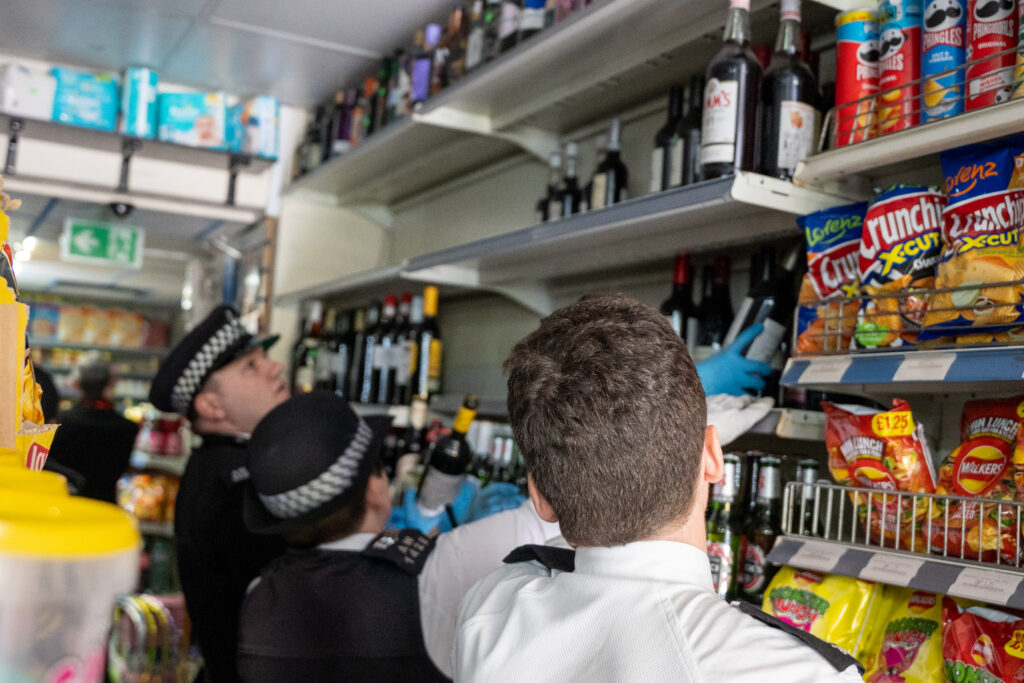 Two officers search shelves in a corner store
