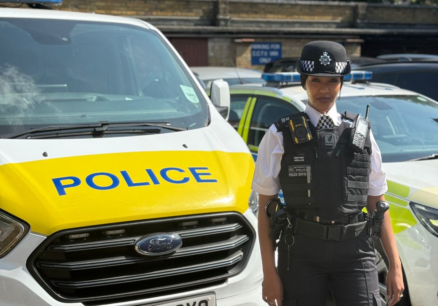 PC Farhiya Abdullahi stands in her Metropolitan Police uniform besides a police van, on a sunny day in London