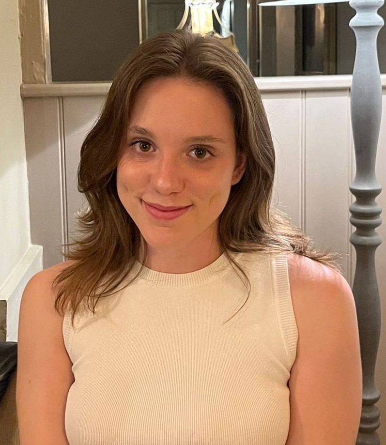 A casual headshot of Vittoria, she is smiling towards the camera and wearing a plain white shirt.