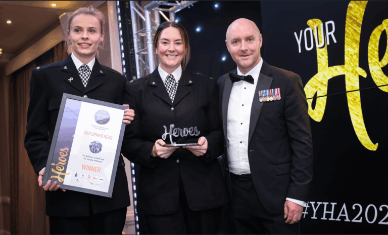 Bethany and Natalie are holding a framed certificate and an award trophy